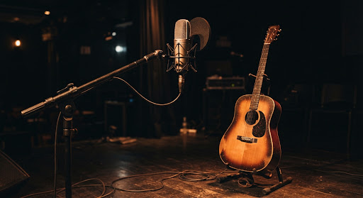 Microfone no palco com violão ao fundo